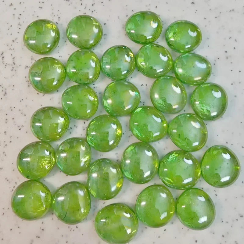 Glossy green glass pebbles scattered on a speckled white surface