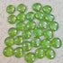 Glossy green glass pebbles scattered on a speckled white surface