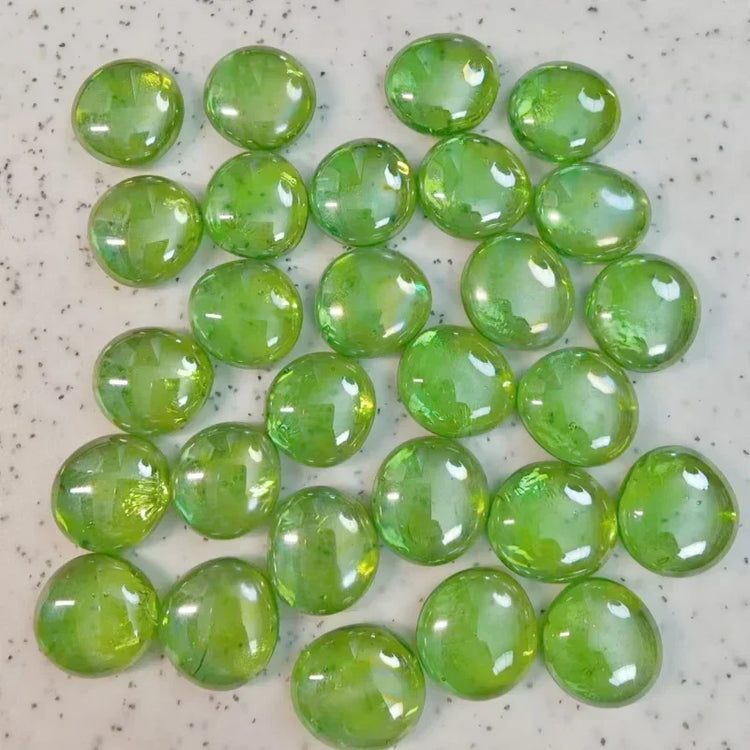 Glossy green glass pebbles scattered on a speckled white surface
