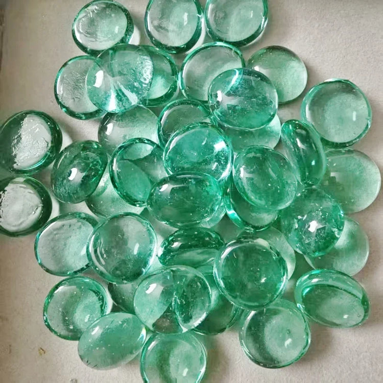 Smooth translucent green glass pebbles scattered on a light surface